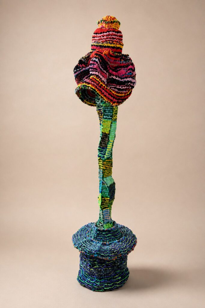 Slender stem topped with a striped orb on a blue base. Pipe cleaner sculpture by Ted Fullwood
