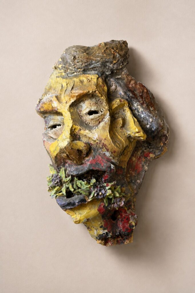 Yellow and red mask with a green beard. Ceramic sculpture by Ted Fullwood