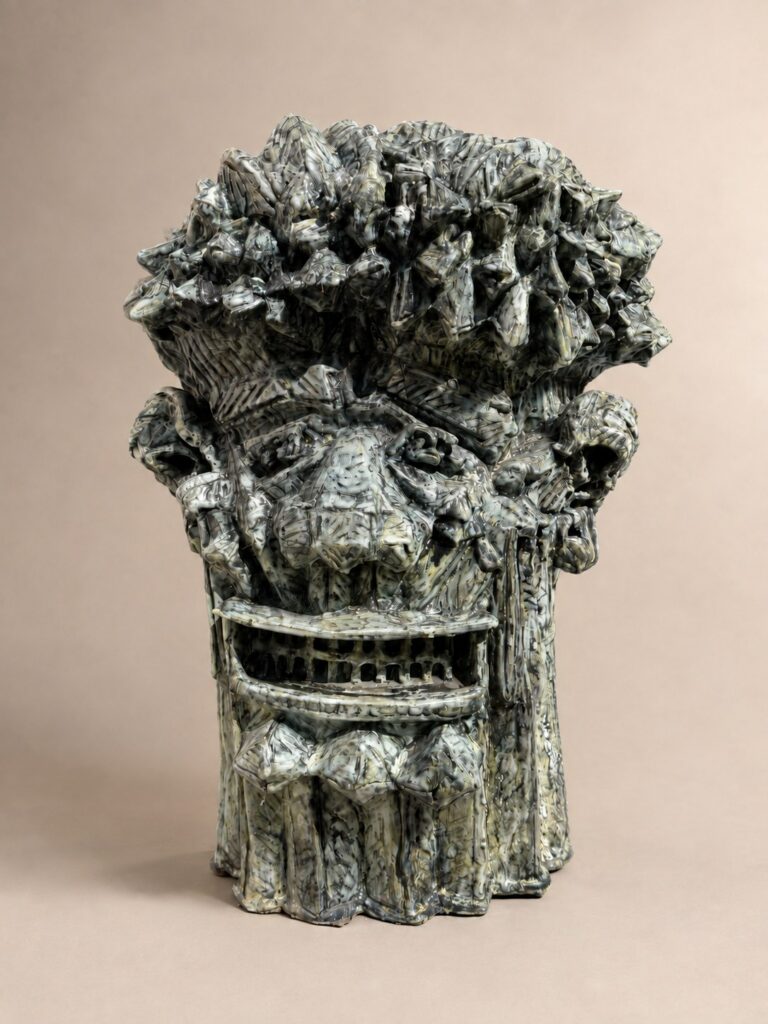 Dark grinning head with spiky hair. Ceramic sculpture by Ted Fullwood